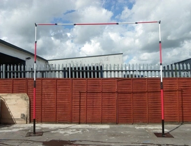 Adjustable height restriction barrier frame with red and white poles at an industrial entrance