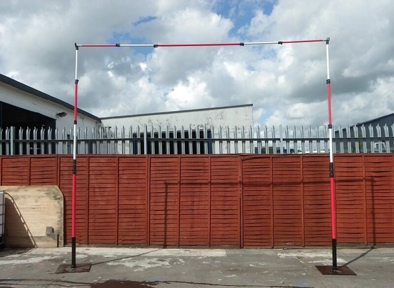 Adjustable height restriction barrier frame with red and white poles at an industrial entrance