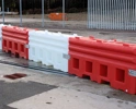 Interlocking red and white water-filled traffic barriers protecting a roadside work area