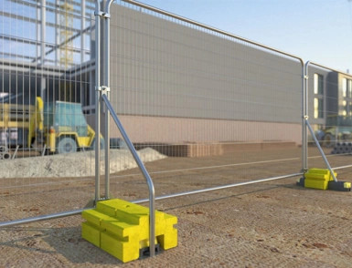 Yellow rubber fencing block holding up temporary fence at a construction site