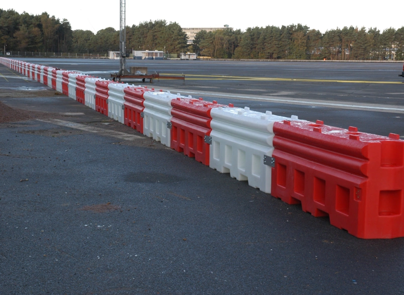 Interlocking red and white water-filled traffic barriers protecting a roadside work area