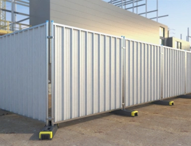 Modular steel hoarding panels with weighted bases forming a temporary site perimeter