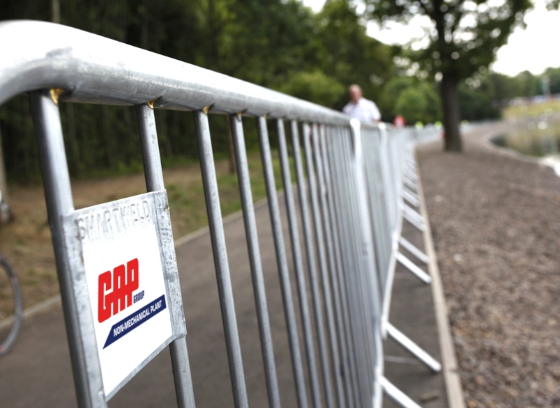 Metal crowd control barriers lining a riverside path for an outdoor event